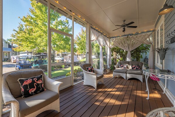 A covered porch with wicker furniture, large windows, and a ceiling fan.