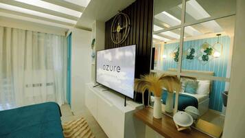 A modern living room with a flat-screen TV, a large mirror, and a bed with a blue and white color scheme.