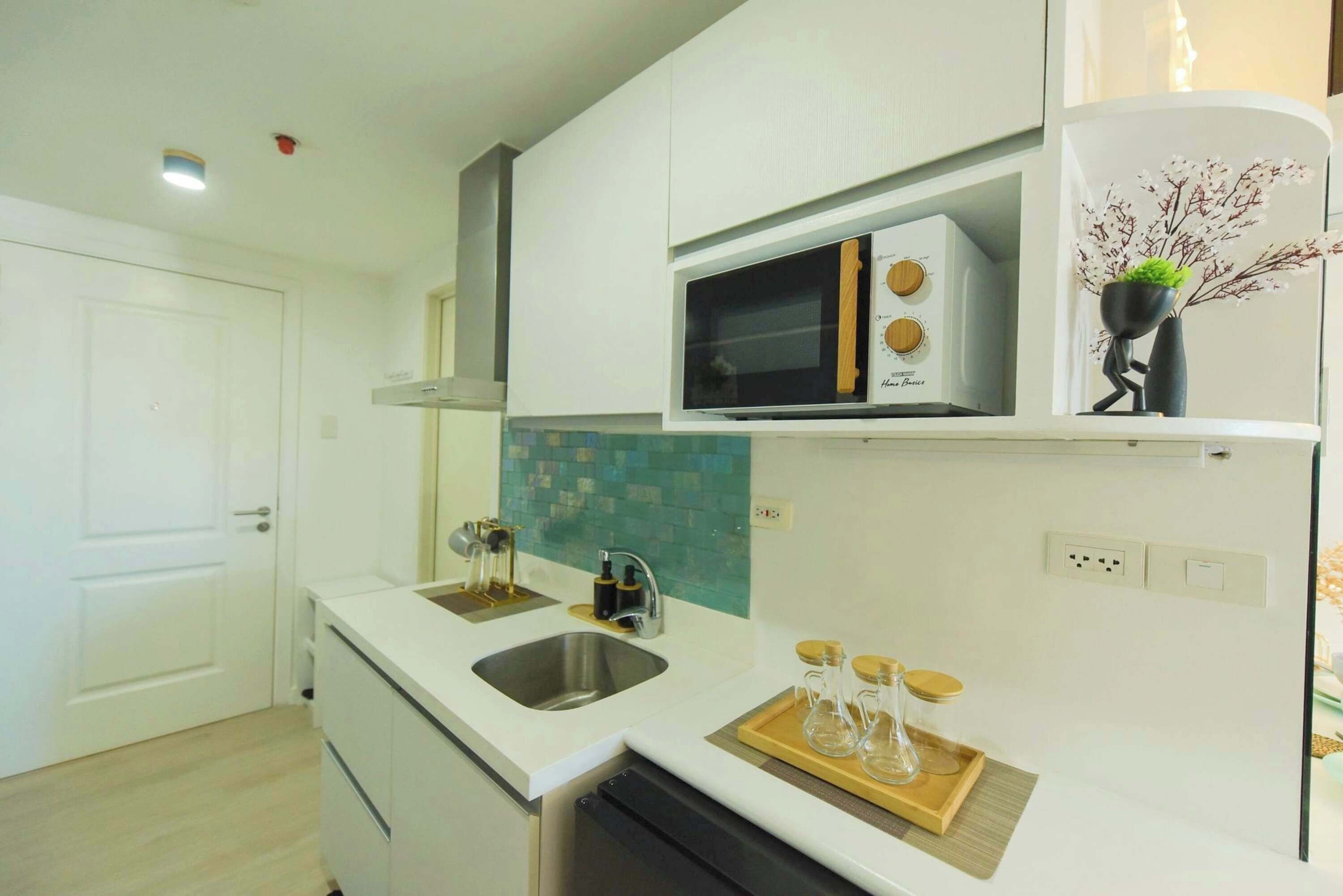 A compact kitchen with white cabinetry, a built-in microwave, and a sink.