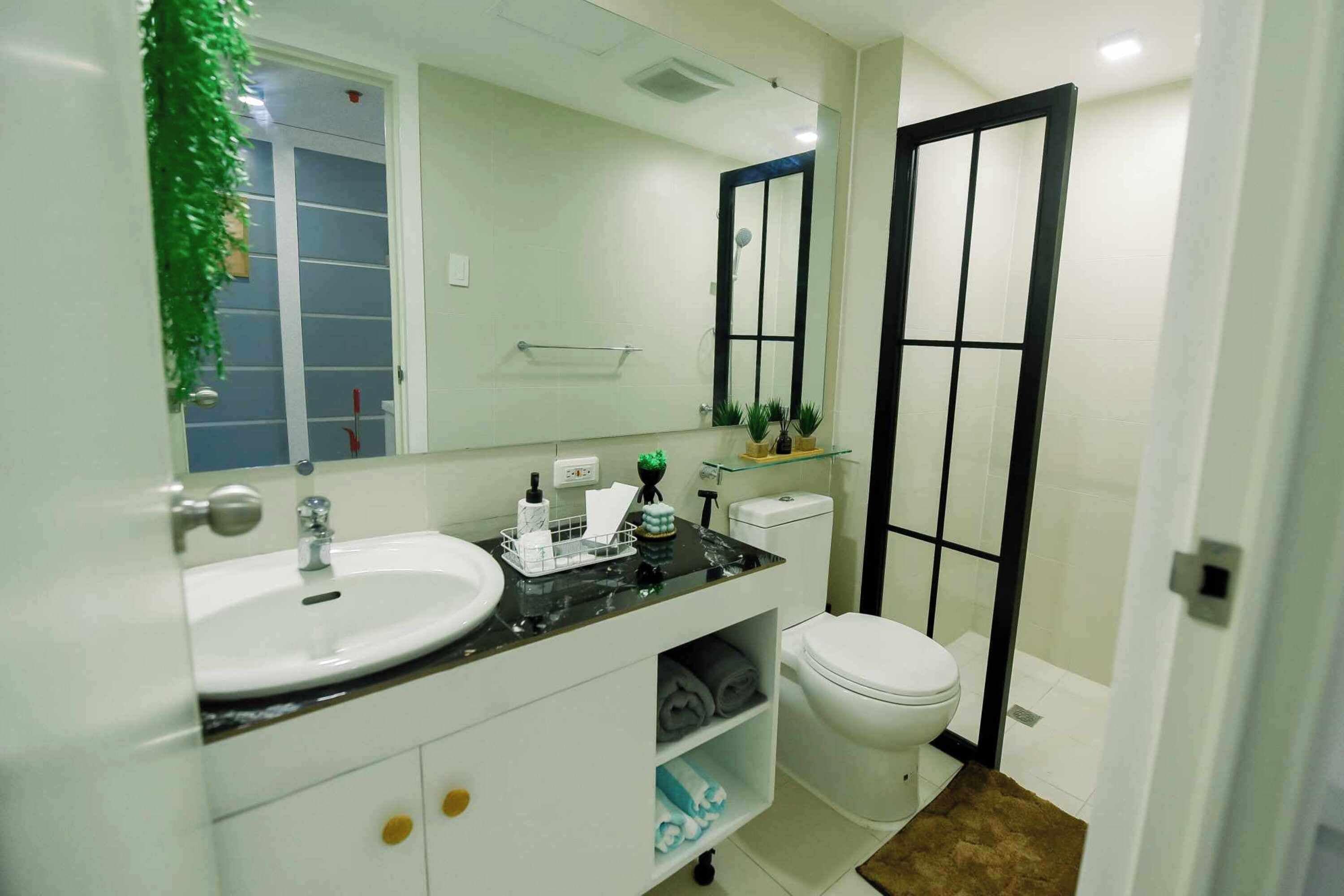 Un baño con un lavamanos blanco, un inodoro y un espejo grande.