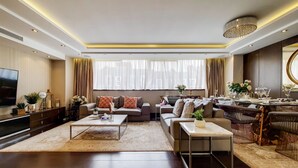 A modern living room with a flat-screen TV, sofas, a coffee table, and a dining area with a chandelier. - The Portman Residences (London)