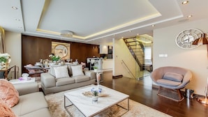 A modern living room with a sofa, coffee table, and a staircase leading to an upper floor. - The Portman Residences (London)