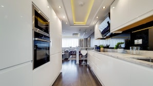 A modern kitchen with white cabinetry, stainless steel appliances, and a wooden floor. - The Portman Residences (London)