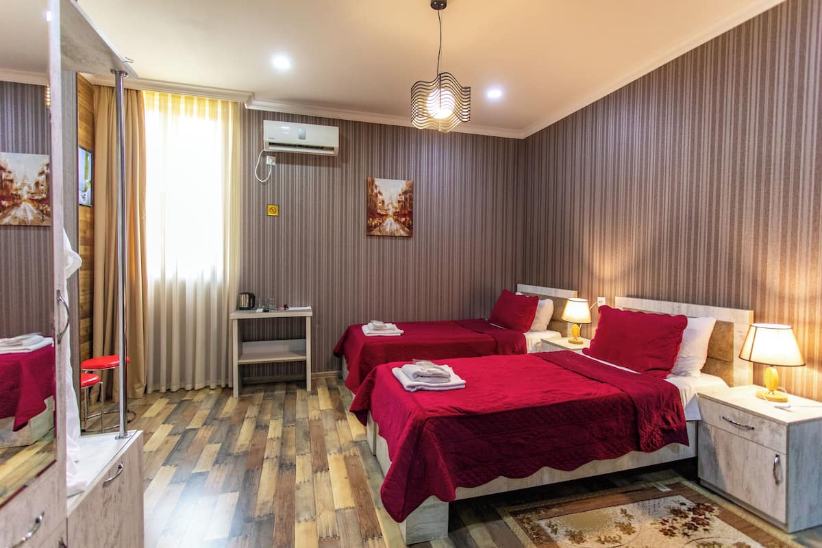Habitación de hotel con dos camas, un escritorio y una silla.