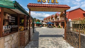 A hotel entrance with a reception area, a covered walkway, and multiple buildings with red roofs. - Hotel Dimasi (Kutaisi)