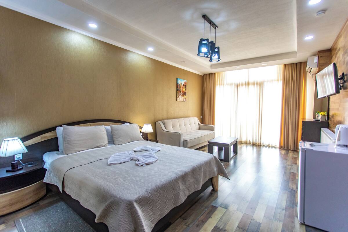 Una habitación de hotel con una cama grande, un sofá, un escritorio y un televisor.