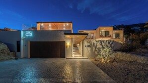 A modern villa with a glass facade, a visible garage, and a well-lit entrance. - Amazing Beach View , Walk to the Beach. Cleaning & Concierge (Cabo San Lucas)