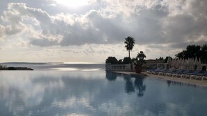 A pool with a view of the sea, surrounded by lounge chairs and palm trees. - Comfortable apartment in Cannes (Cannes)