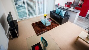 A modern apartment with a living room, kitchen, and a balcony with blinds. - Meridian Tower Apartment (Swansea)