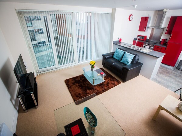Un apartamento moderno con sala de estar, cocina y un balcón con persianas.