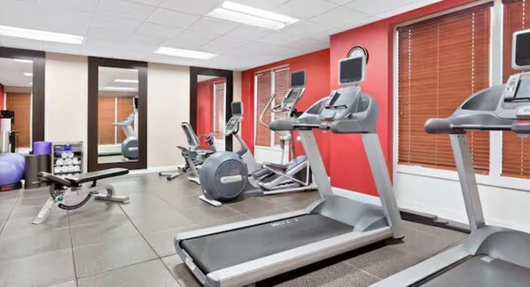 A gym with treadmills, elliptical machines, and a weight bench.