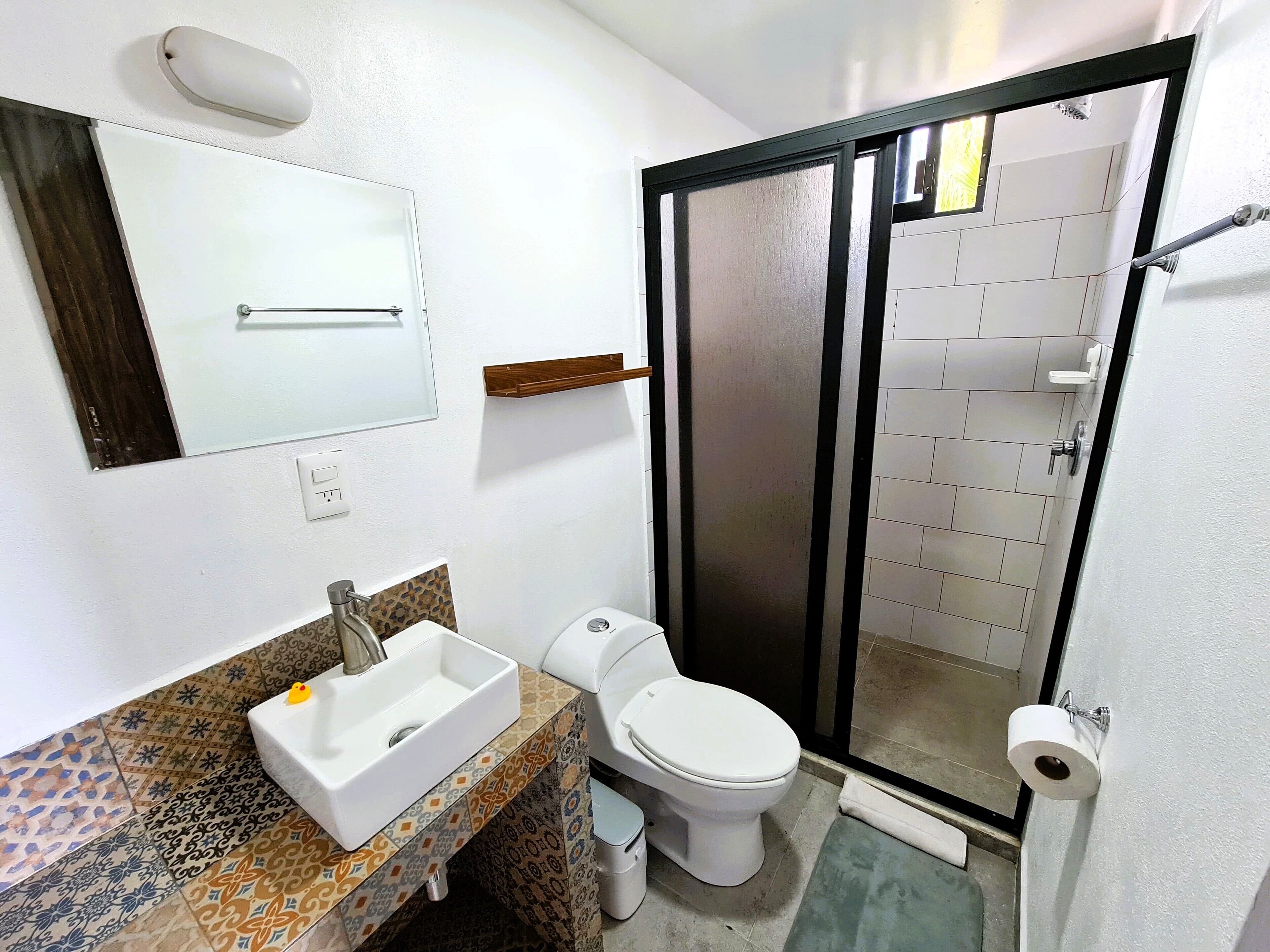 Une salle de bain avec un lavabo, des toilettes et une douche, le tout de couleur blanche.