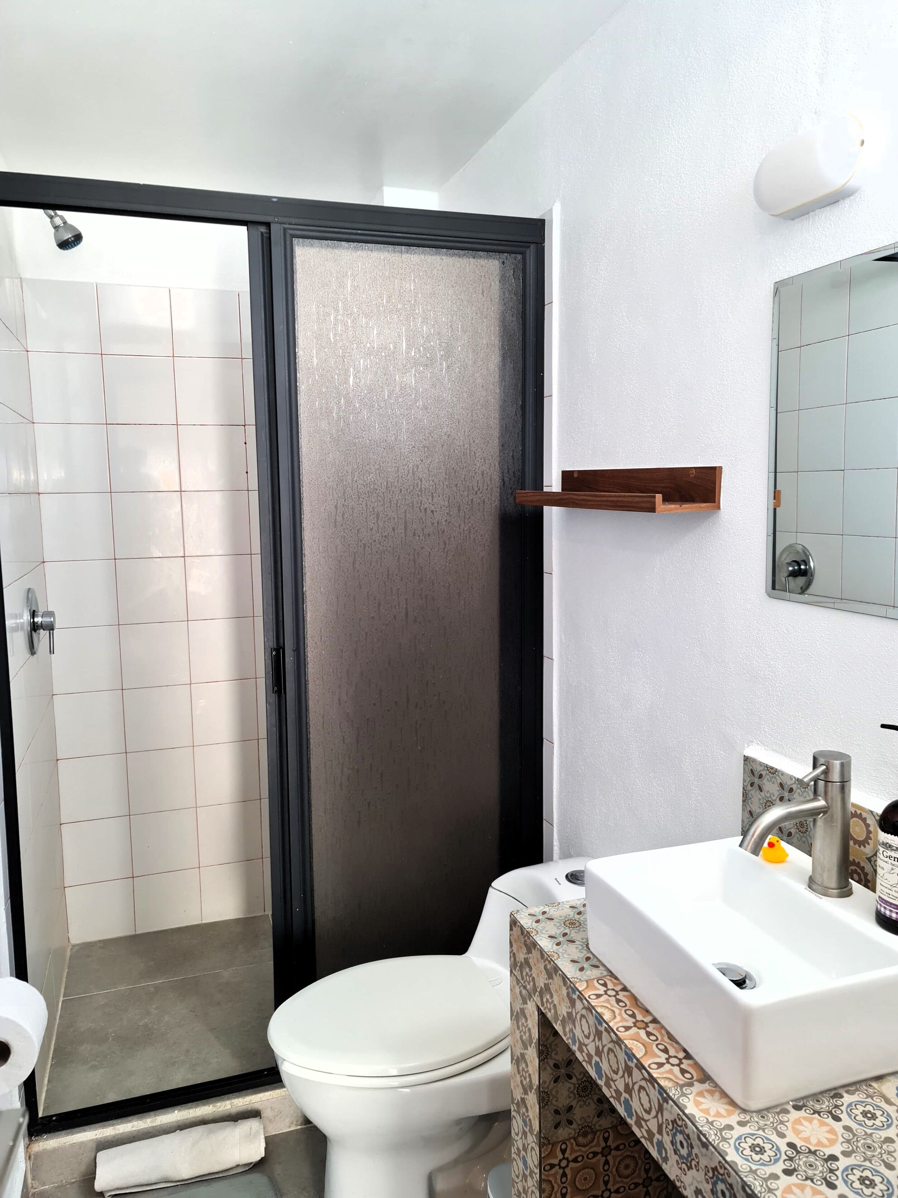 A bathroom with a toilet, sink, and shower area.
