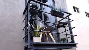 Un balcon avec une chaise, des plantes en pot et une fenêtre.