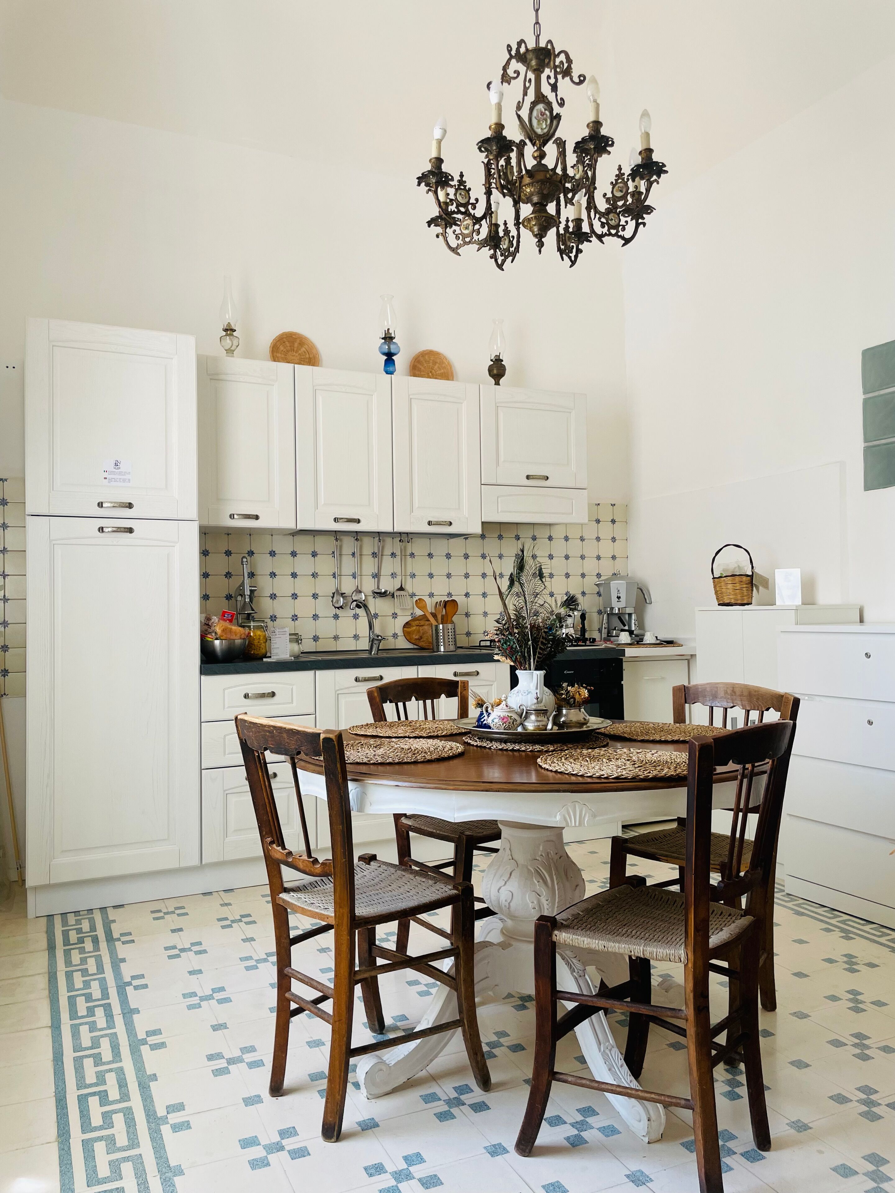 A kitchen with white cabinets, a dining table with chairs, and a chandelier.