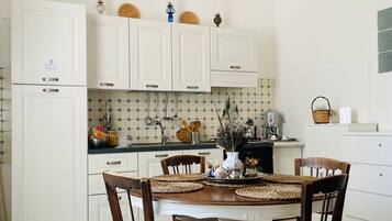 A kitchen with white cabinets, a dining table with chairs, and a chandelier.