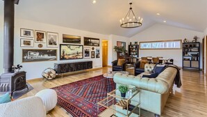 A spacious living room with a fireplace, comfortable seating, a large rug, and a variety of wall art.