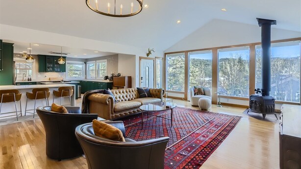 A spacious living room with a large window, a fireplace, and a kitchen area.