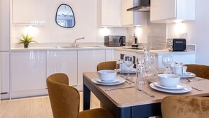 A modern kitchen with white cabinetry, a built-in oven, a microwave, and a coffee maker. - Victoria Square Two-bed Accommodation by Belvilla (Birmingham)
