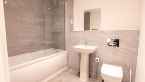 A modern bathroom with a glass-enclosed shower, a standalone sink, and a toilet. - Victoria Square Two-bed Accommodation by Belvilla (Birmingham)