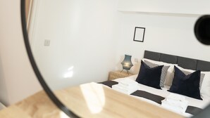 Ein modernes Schlafzimmer mit Bett, Nachttisch, Lampe und einem gerahmten Bild an der Wand.