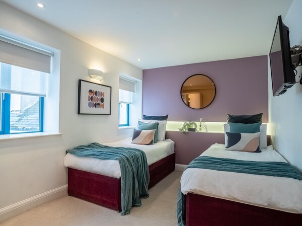 A modern bedroom with two beds, a large mirror, and a TV. - 2BR Harbor View Near Babbacoombe Selfcheck-in (Torquay)