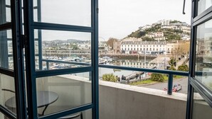 A balcony with a view of a marina and buildings on a hill.