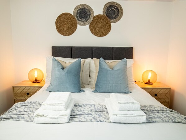 A neatly made bed with two pillows, two bedside lamps, and a wall-mounted decorative item. - One-bedroom Near Torquay Museum by Belvilla (Torquay)