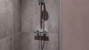 A shower with a handheld showerhead and a fixed wall-mounted showerhead.
