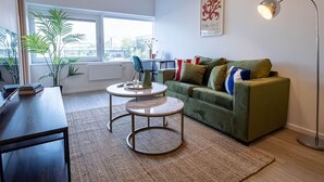 A modern living room with a green sofa, a round coffee table, and a floor lamp.