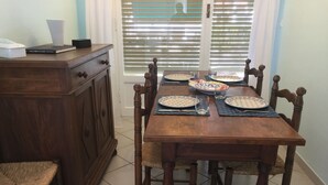 Een eettafel gedekt met borden, glazen en bestek, omringd door houten stoelen en een houten kast.