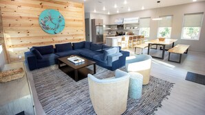 A modern living room with a sectional sofa, a coffee table, and a dining area with a bench. - North Firefly - Resort Pool, 2-min. walk to Private Beach! (Saint Teresa)