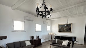 A spacious living room with a piano, a chandelier, and a large window. - La casa di Pippo Flora (Agrigento)