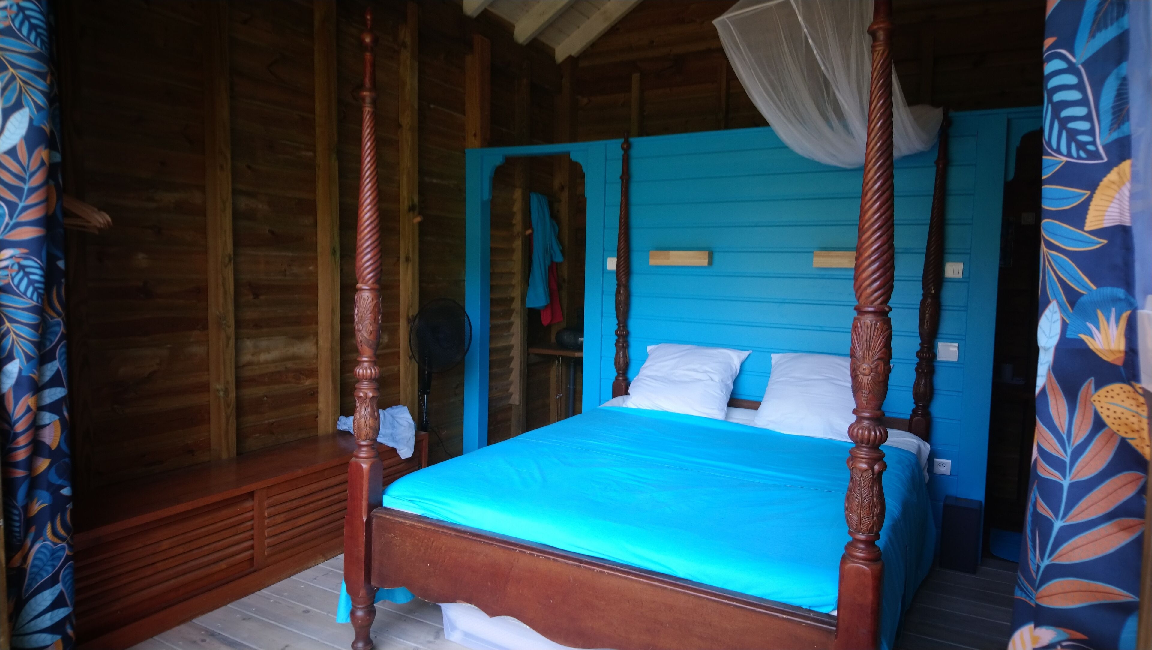 Ein Himmelbett mit blauer Bettdecke, Holzwänden und Holzboden.