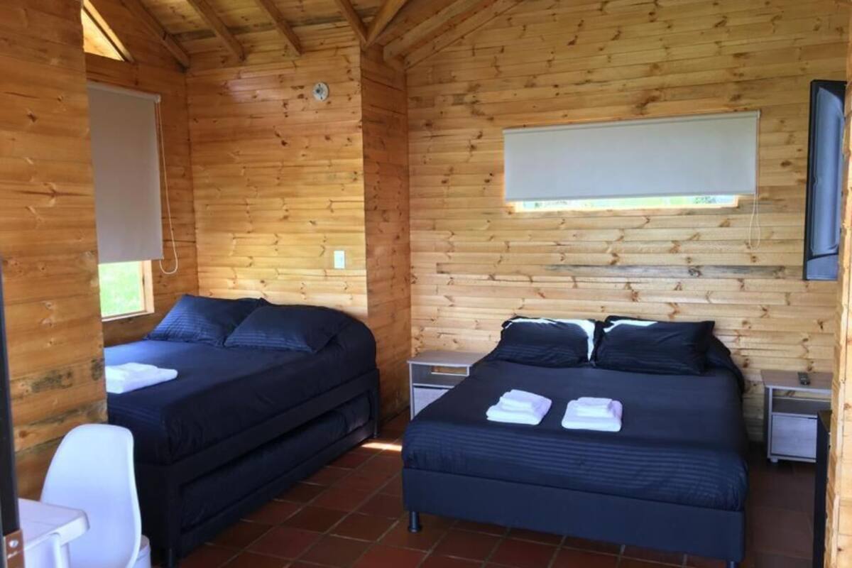 A cabin with two beds, a small table, and a chair.