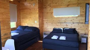 En stuga med två sängar, ett litet bord och en stol.