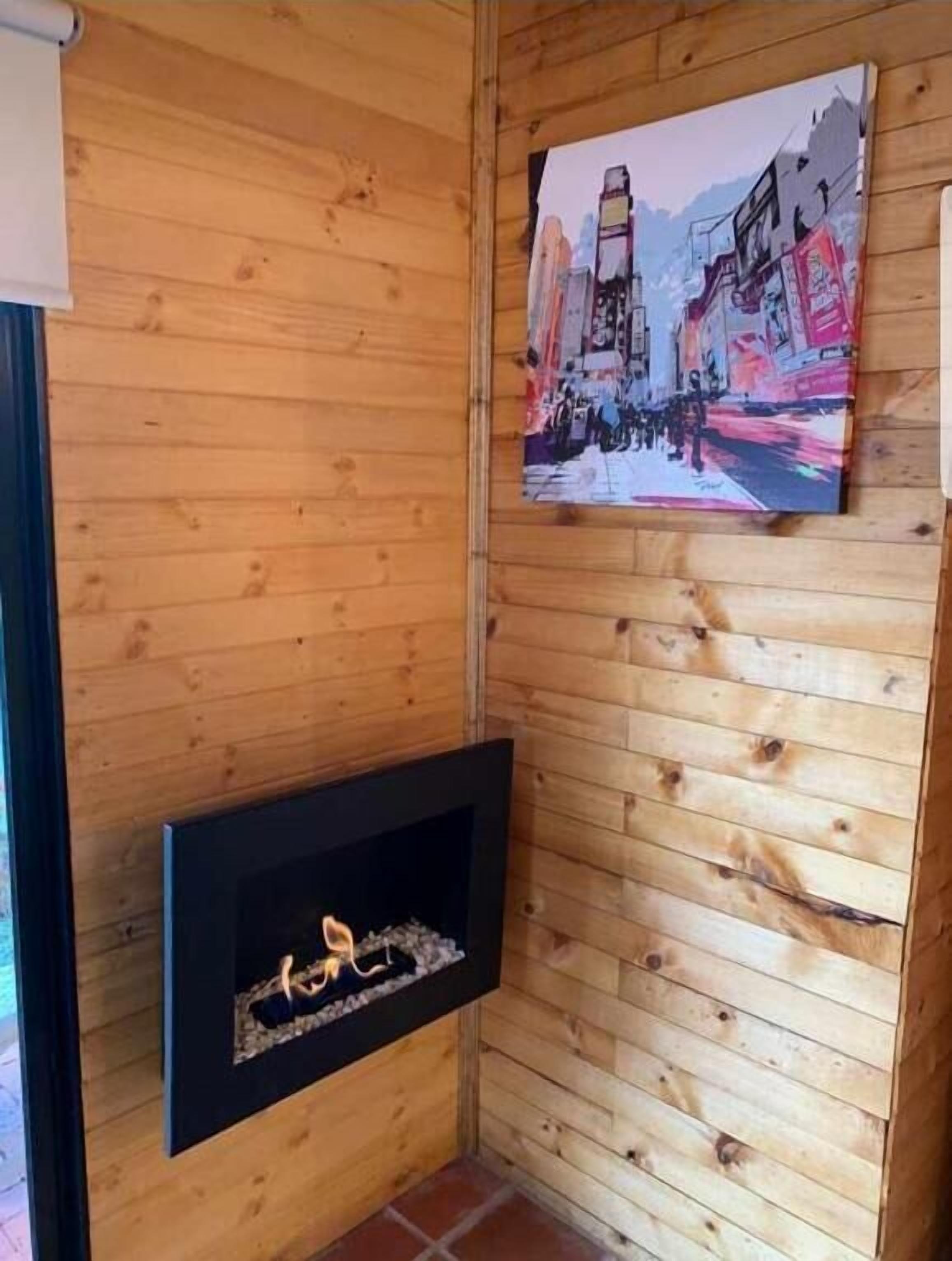 Un interior de madera con chimenea y un cuadro de un paisaje urbano en la pared.
