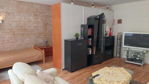 A modern living room with a sofa, a glass coffee table, a TV, and a bookshelf. - 5 Minuten von Frankfurt, Ruhige Ferienwohnung/ Monteurzimmer mit Terrasse (Bad Vilbel)