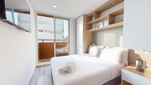 A modern hotel room with a large bed, a wooden headboard, a built-in shelf with decorative items, and a sliding glass door leading to a balcony. - gAº Espectacular apartamento en La Cabrera (Bogotá)