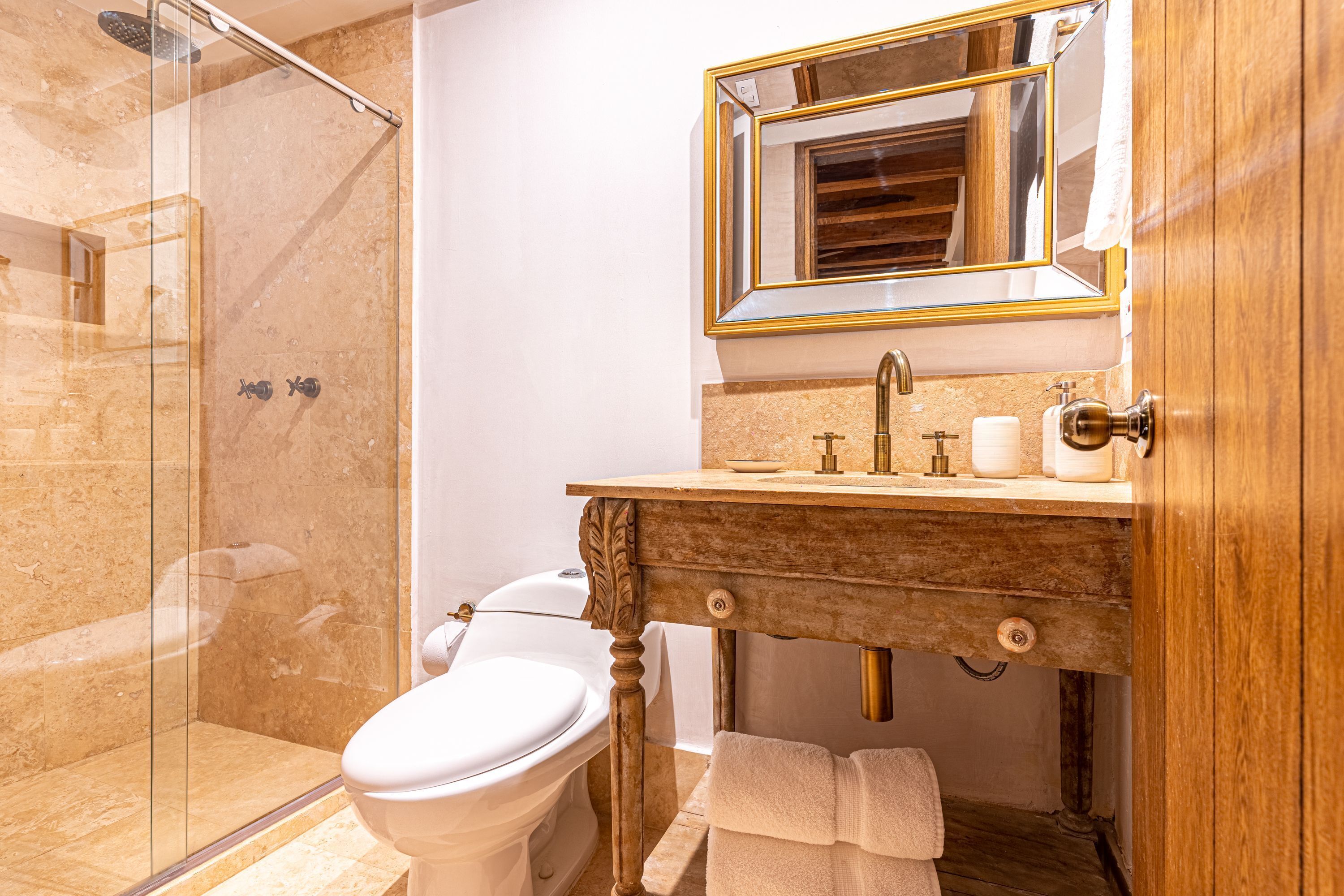 A bathroom with a glass-enclosed shower, a toilet, a vanity with a mirror, and a towel rack.
