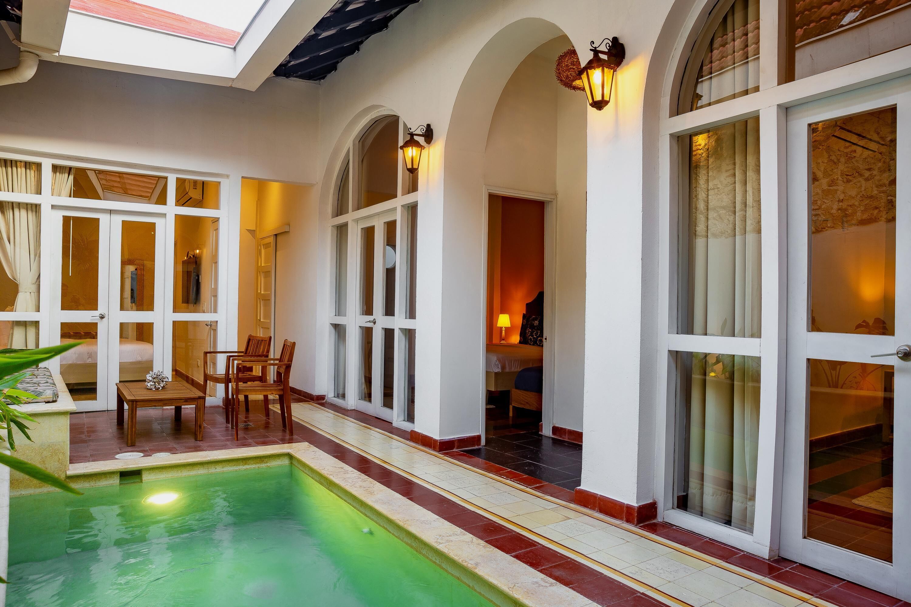 A pool area with a sunken seating area, arched doorways, and a view into the interior of the building.