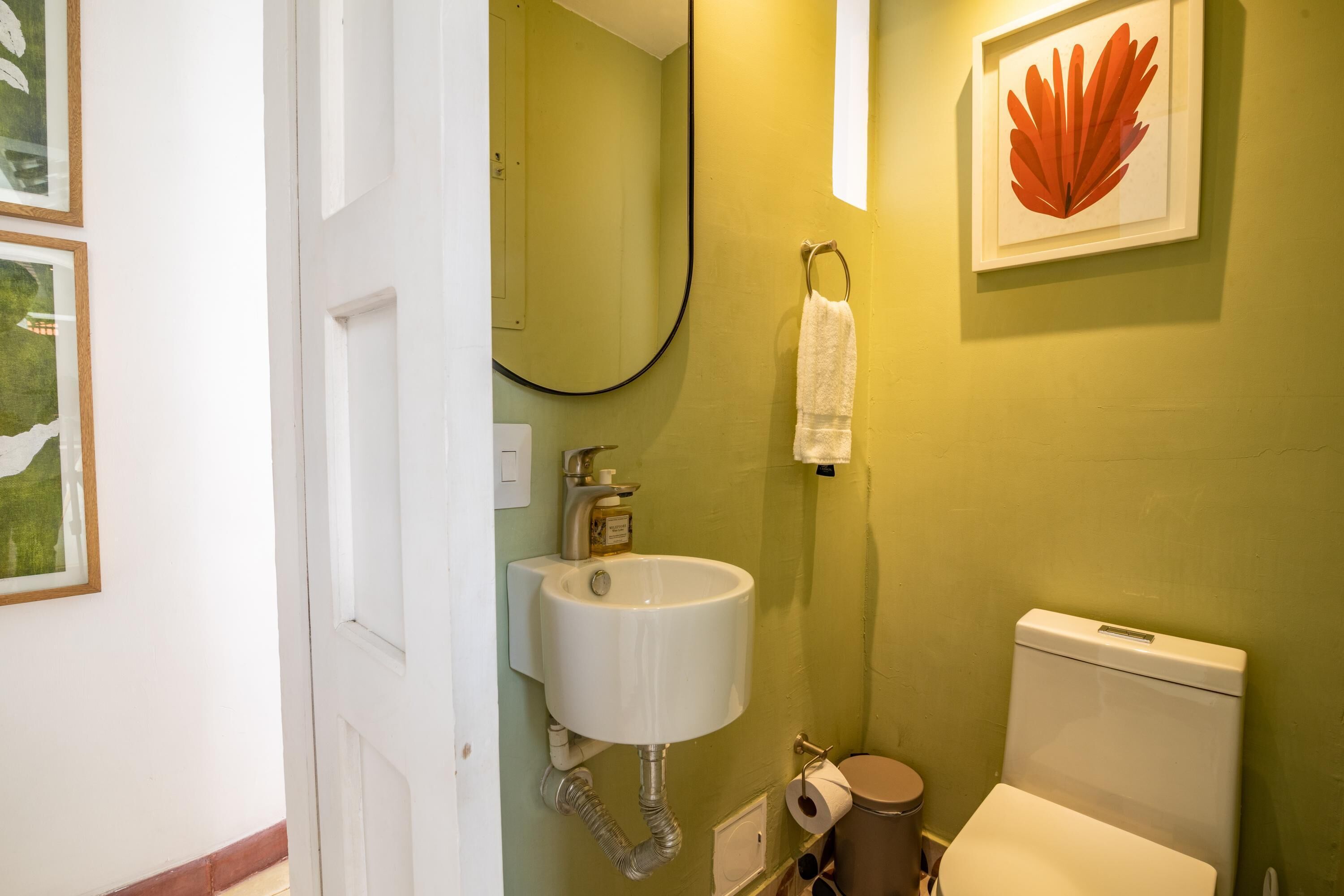 Une salle de bain avec un lavabo blanc, des toilettes et une œuvre d’art encadrée accrochée au mur.