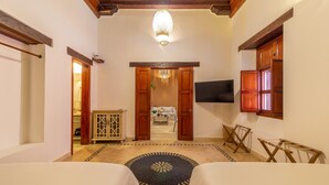 A hotel room with two beds, a wooden ceiling, a chandelier, a TV, and a view of the living area. - Casa Amande - Luxury House (Cartagena)