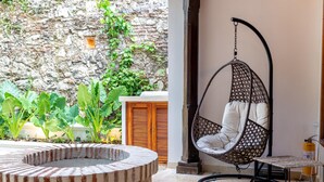 A circular stone fire pit, a hanging chair, and a small table with a tiled floor. - Casa Amande - Luxury House (Cartagena)