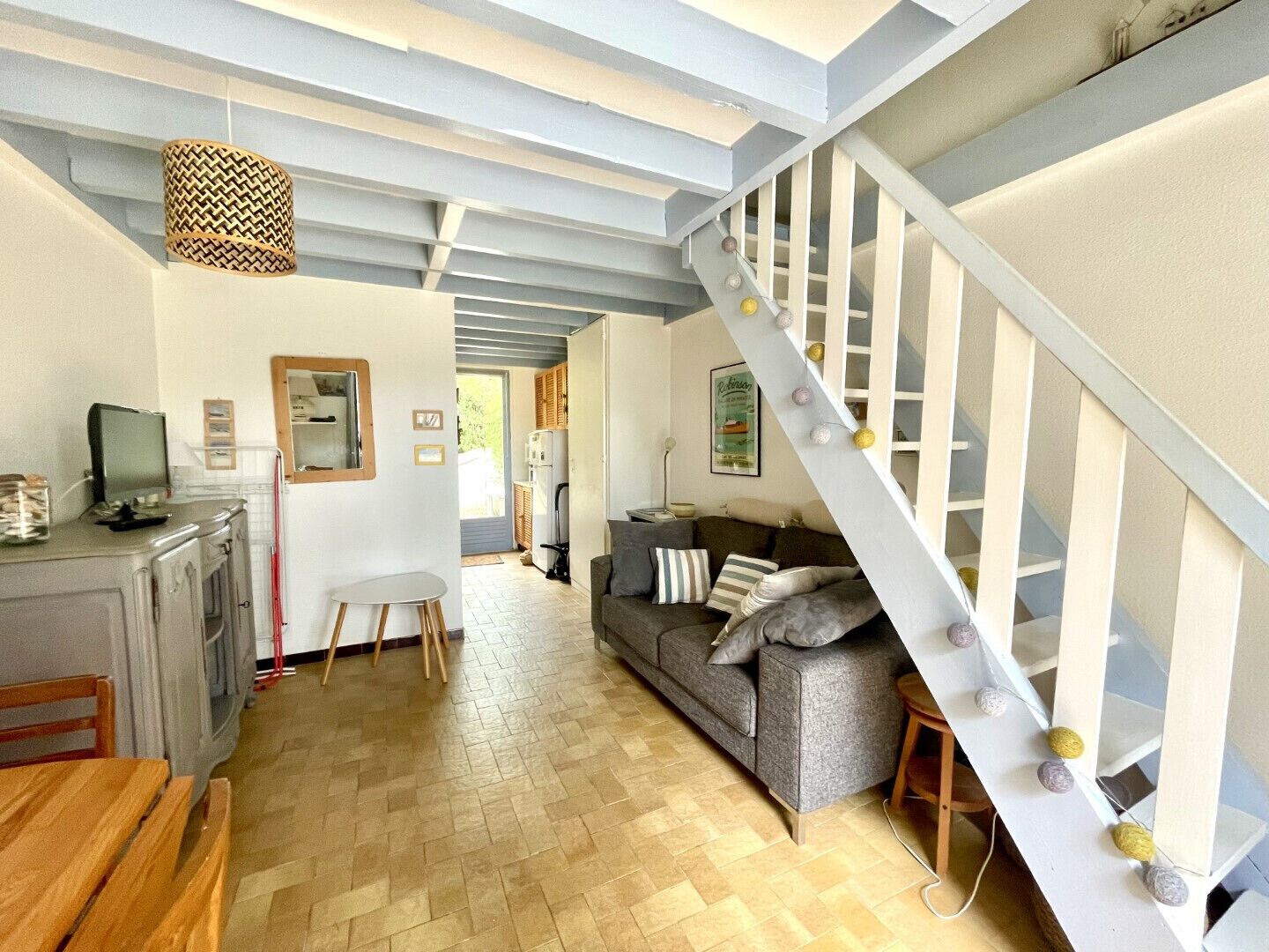 Amplia sala de estar con escalera, cocina y comedor.