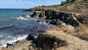 A coastal landscape with rocky cliffs, a clear sky, and a path leading to the sea. - Vrbo Property
(Laroque-des-Albères)