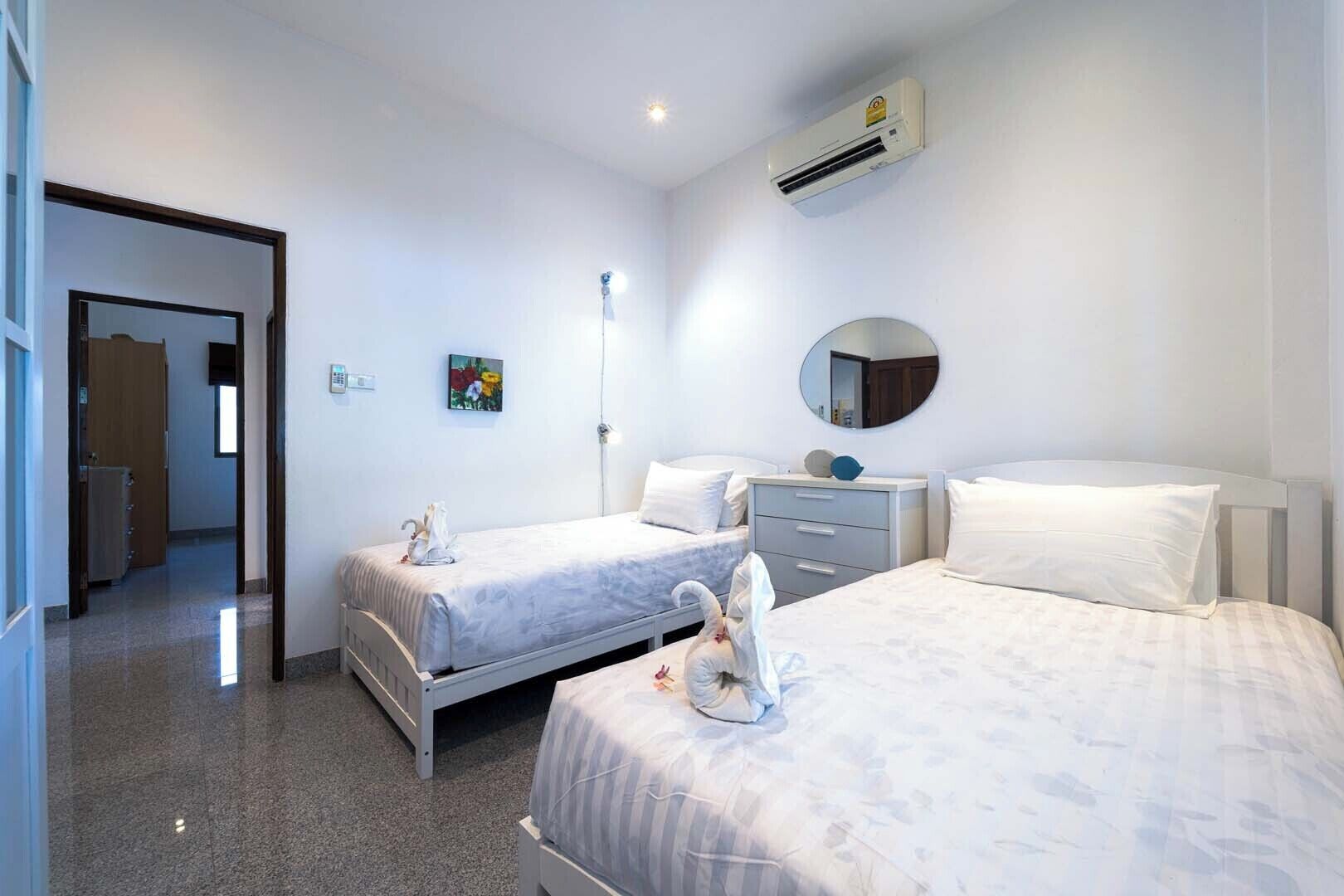 Een hotelkamer met twee bedden, een nachtkastje, een spiegel en een airconditioning.