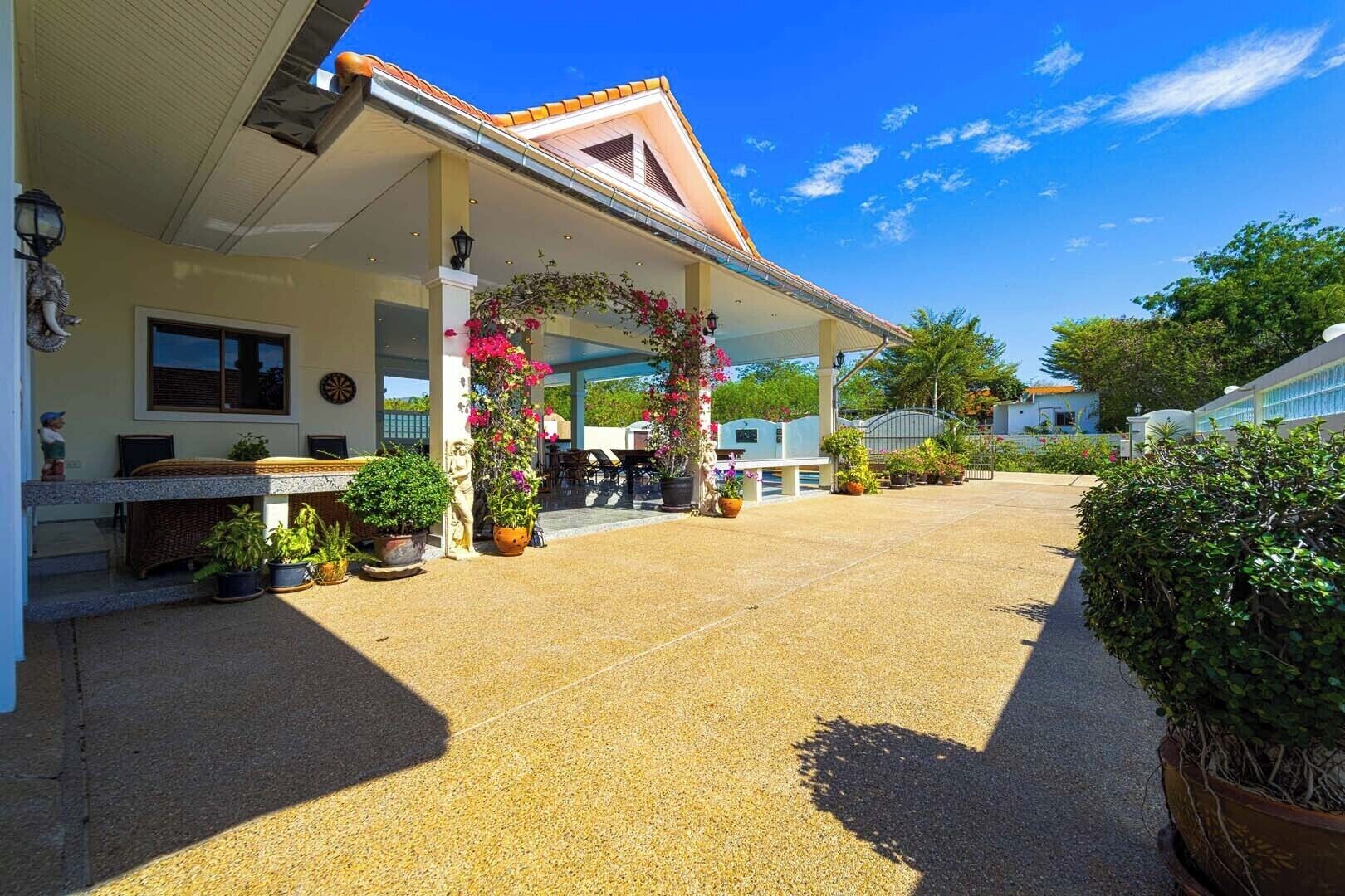 A covered outdoor area with a patio, potted plants, and a building entrance.