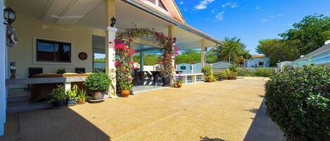 A covered outdoor area with a patio, potted plants, and a building entrance.