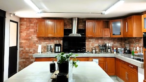 A modern kitchen with wooden cabinets, a central island, and a brick accent wall.
